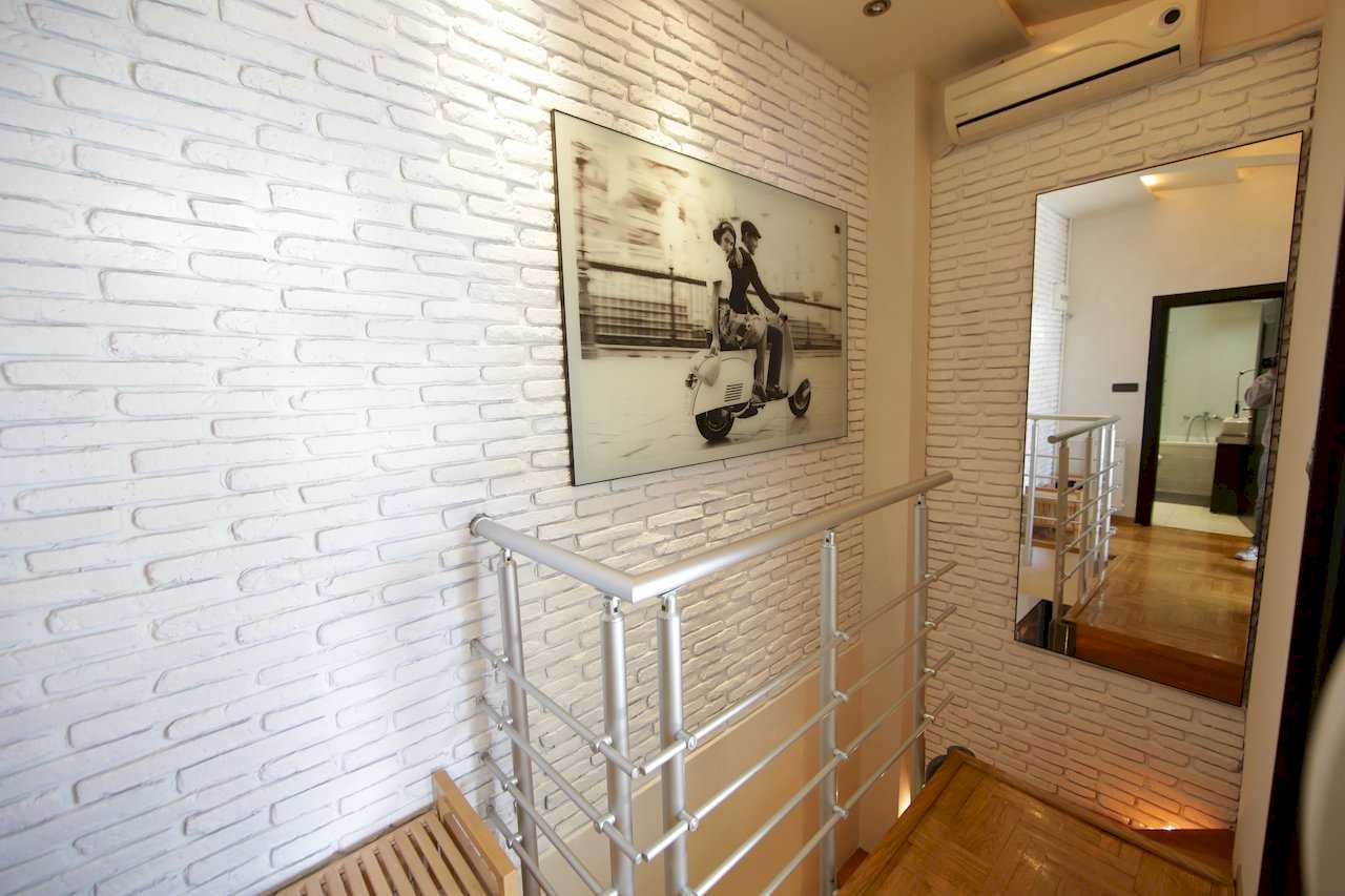 Hallway with white brick wall, mirror and staircase – Apartment Arena – City Break Apartments