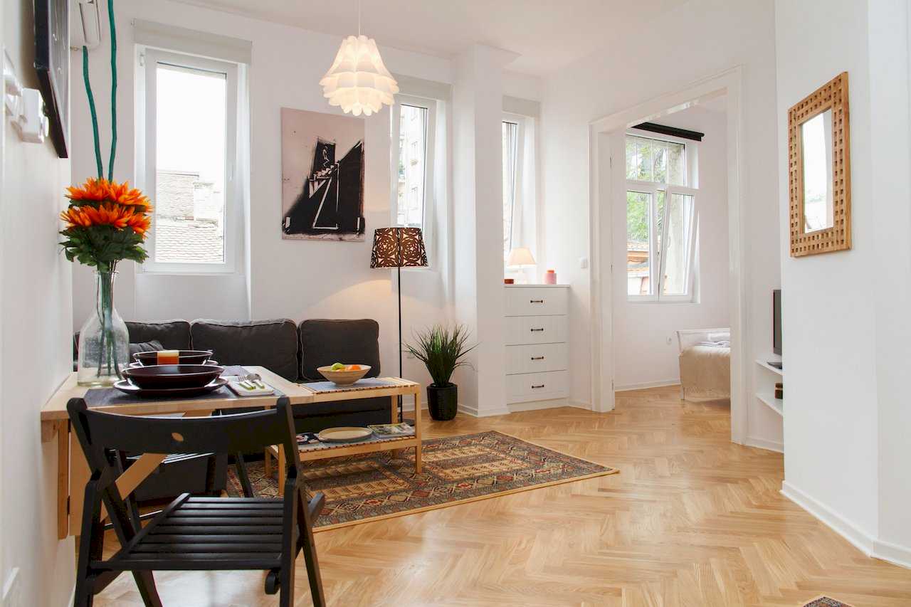 Dnevna soba i trpezarija sa velikim prozorima i pogledom ka spavaćoj sobi – Apartman Atelje 1 – City Break Apartments