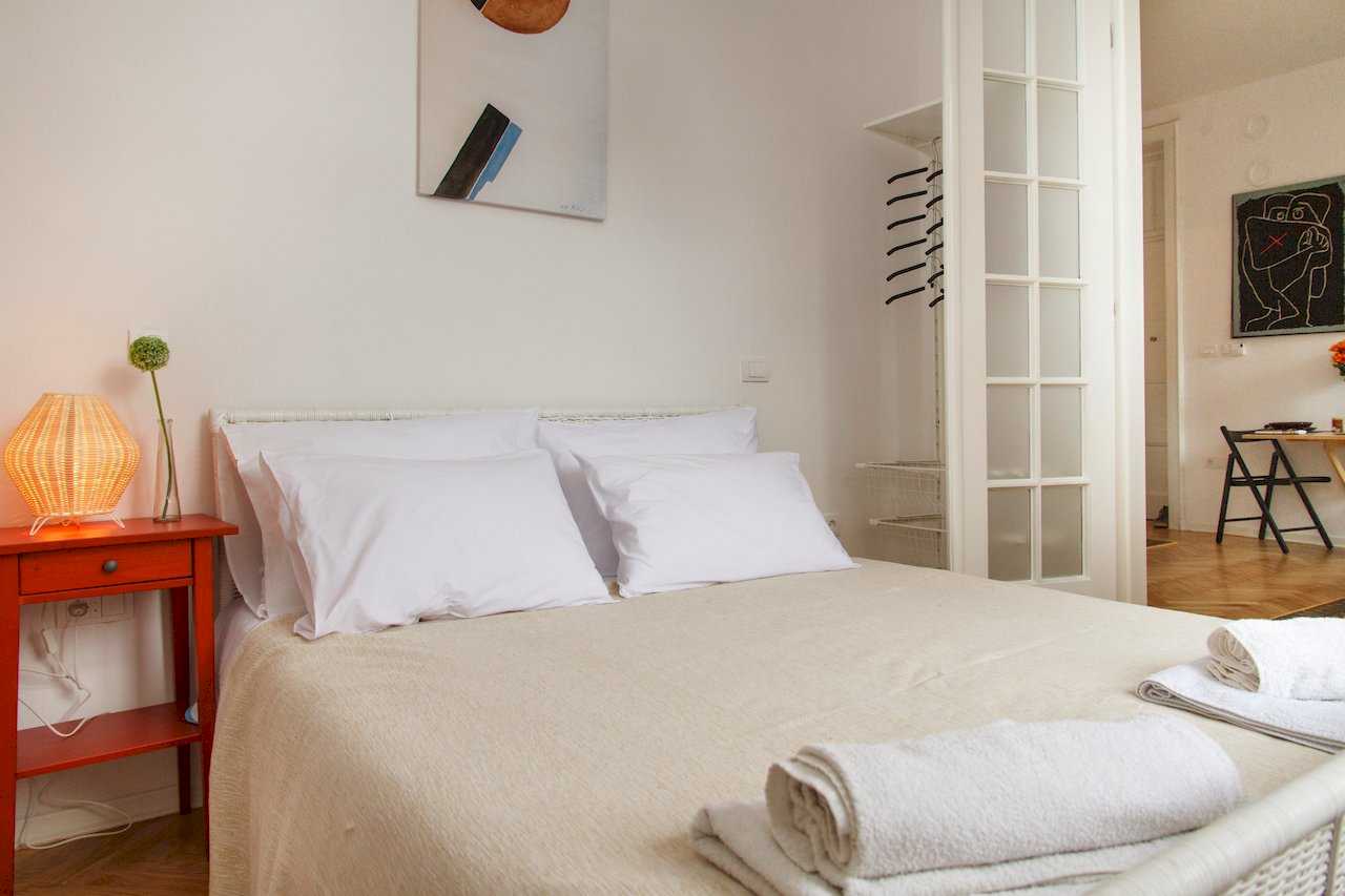 Spavaća soba sa bračnim krevetom i otvorenim garderoberom pored vrata – Apartman Atelje 1 – City Break Apartments