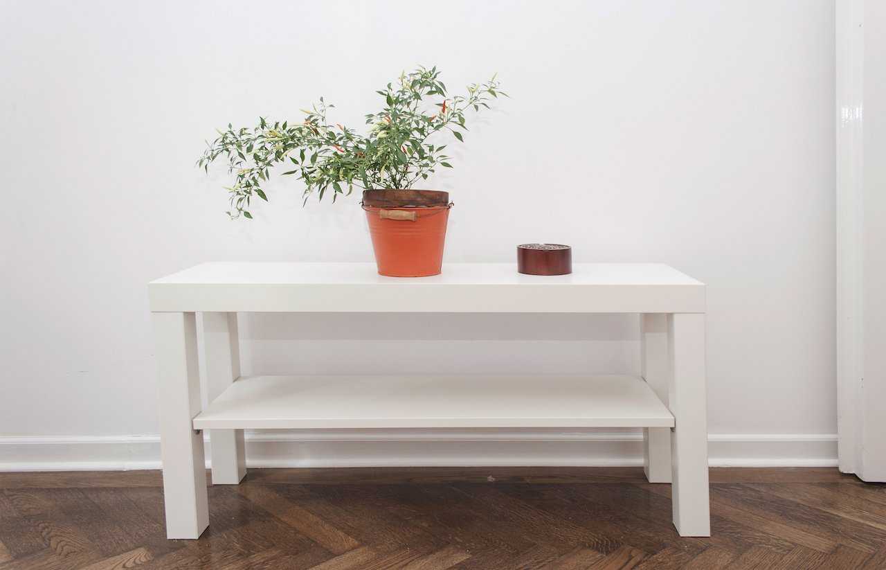Hallway – white two-tier bench, orange enamel bucket pot with a red-berry shrub and small wooden lidded box on herringbone parquet – Apartment Atelje 2 – City Break Apartments