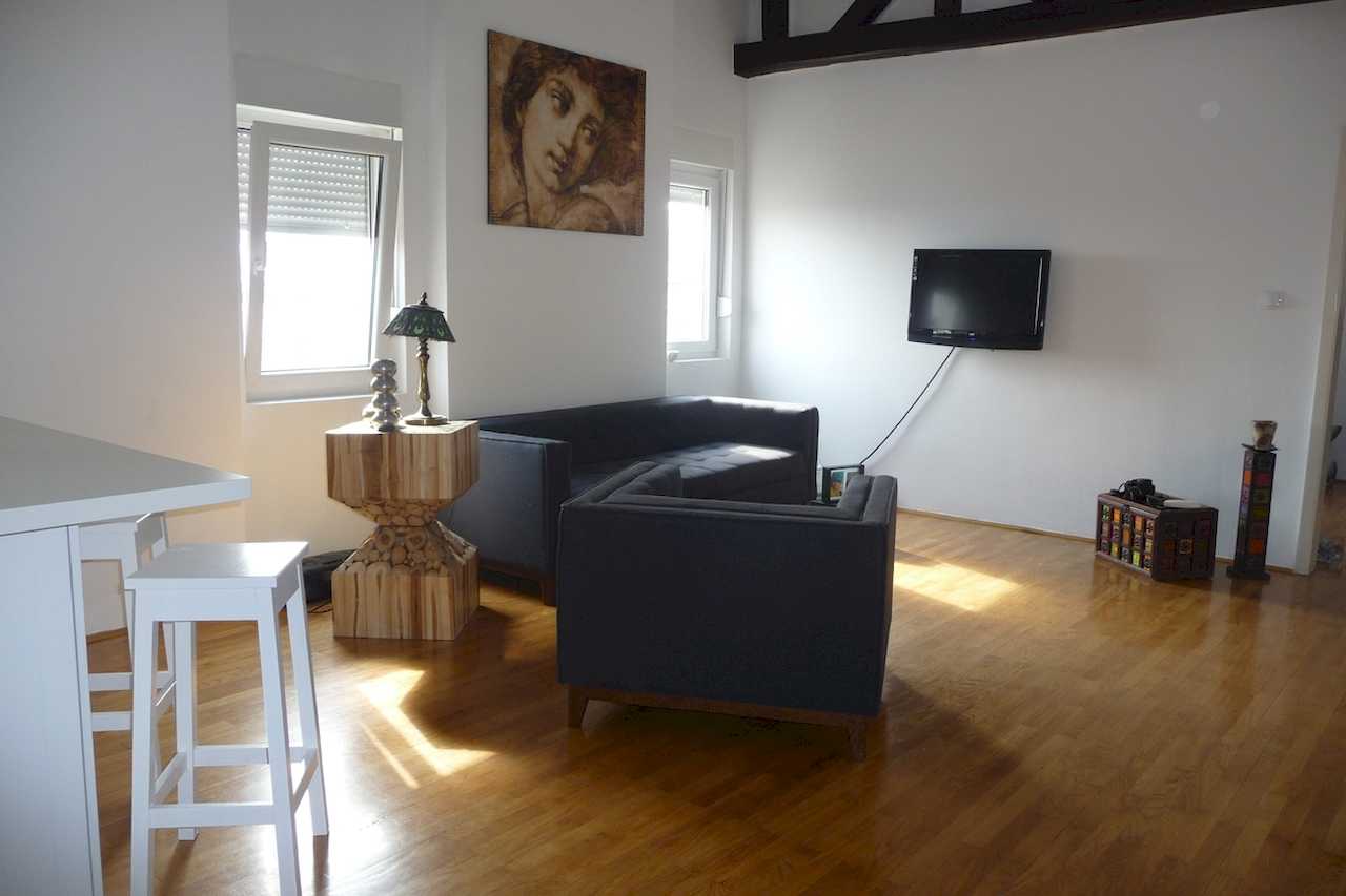 Dnevna soba sa sofom, foteljom i TV-om na zidu – Apartman Belgrade Sky – City Break Apartments