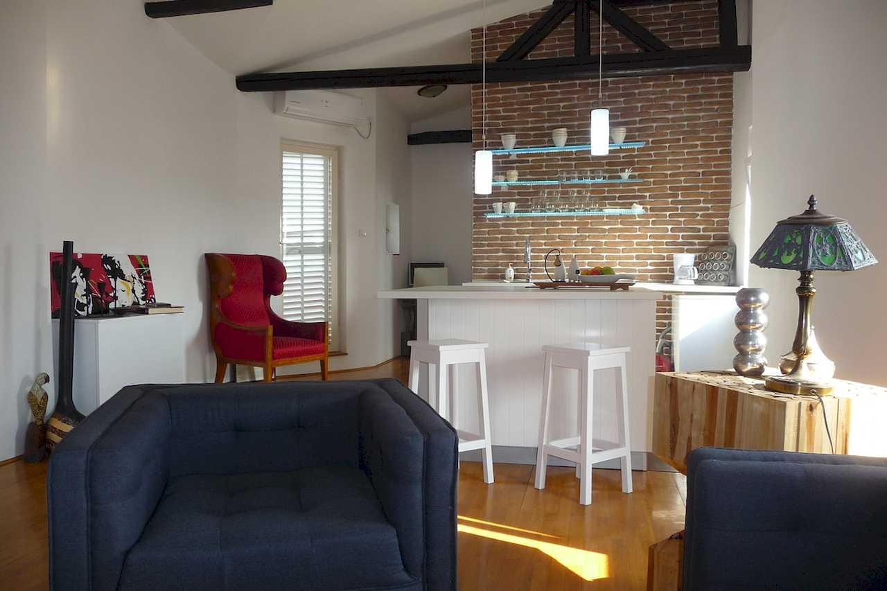 Dnevna soba i kuhinja sa ostrvom, dekor i rustični plafonski nosači – Apartman Belgrade Sky – City Break Apartments
