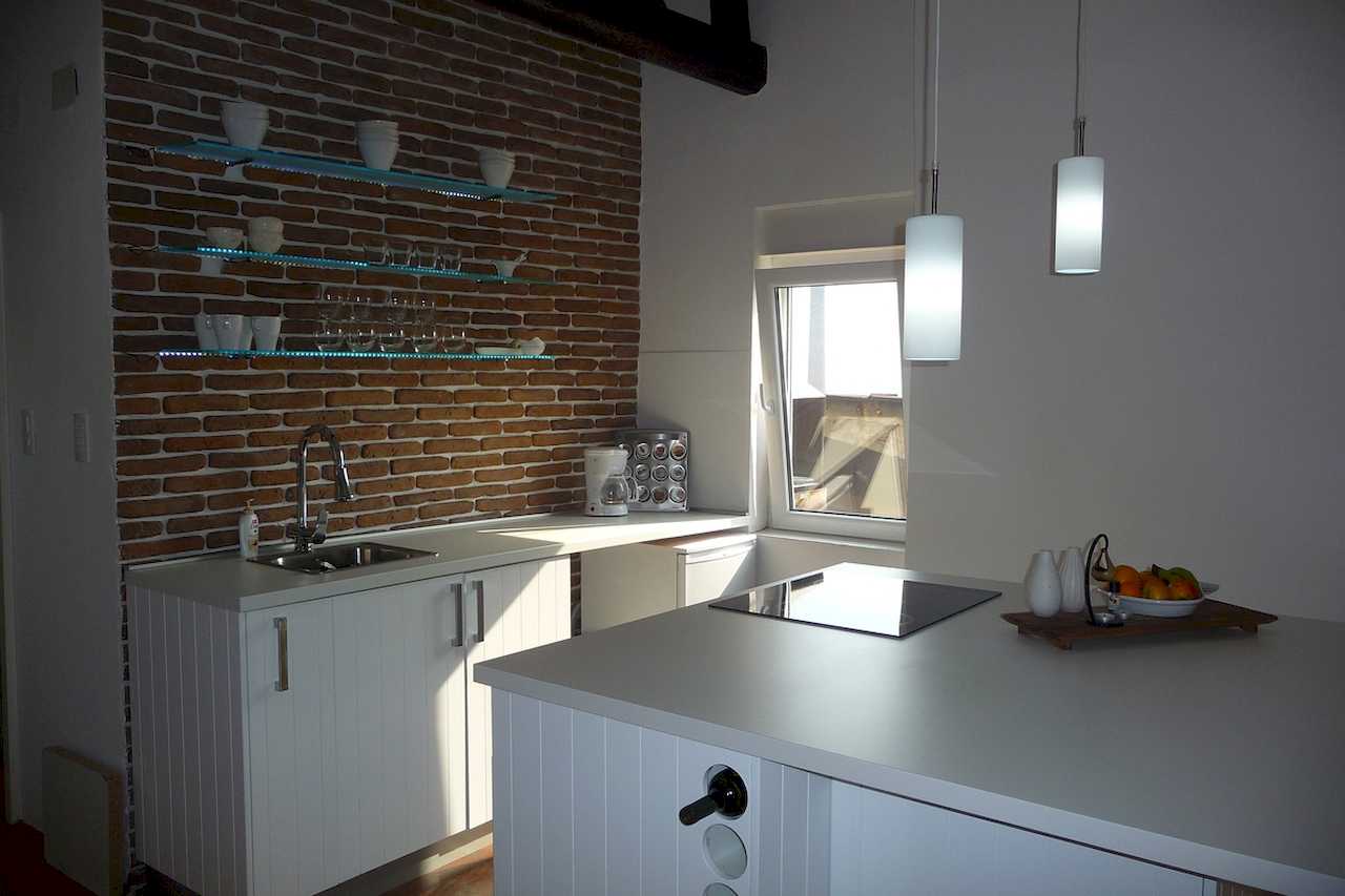 Kuhinja sa ostrvom i ciglanim zidom, viseća rasveta i aparat za kafu – Apartman Belgrade Sky – City Break Apartments
