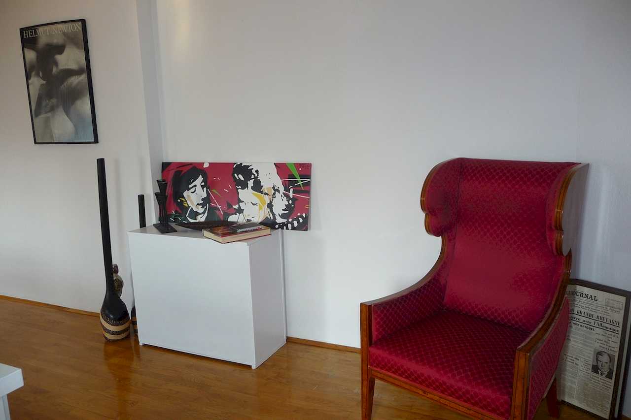 Crvena fotelja i dekorativni kutak sa slikom na zidu – Apartman Belgrade Sky – City Break Apartments