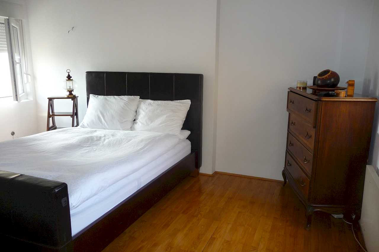 Spavaća soba sa bračnim krevetom i komodom, pogled ka prozorima – Apartman Belgrade Sky – City Break Apartments