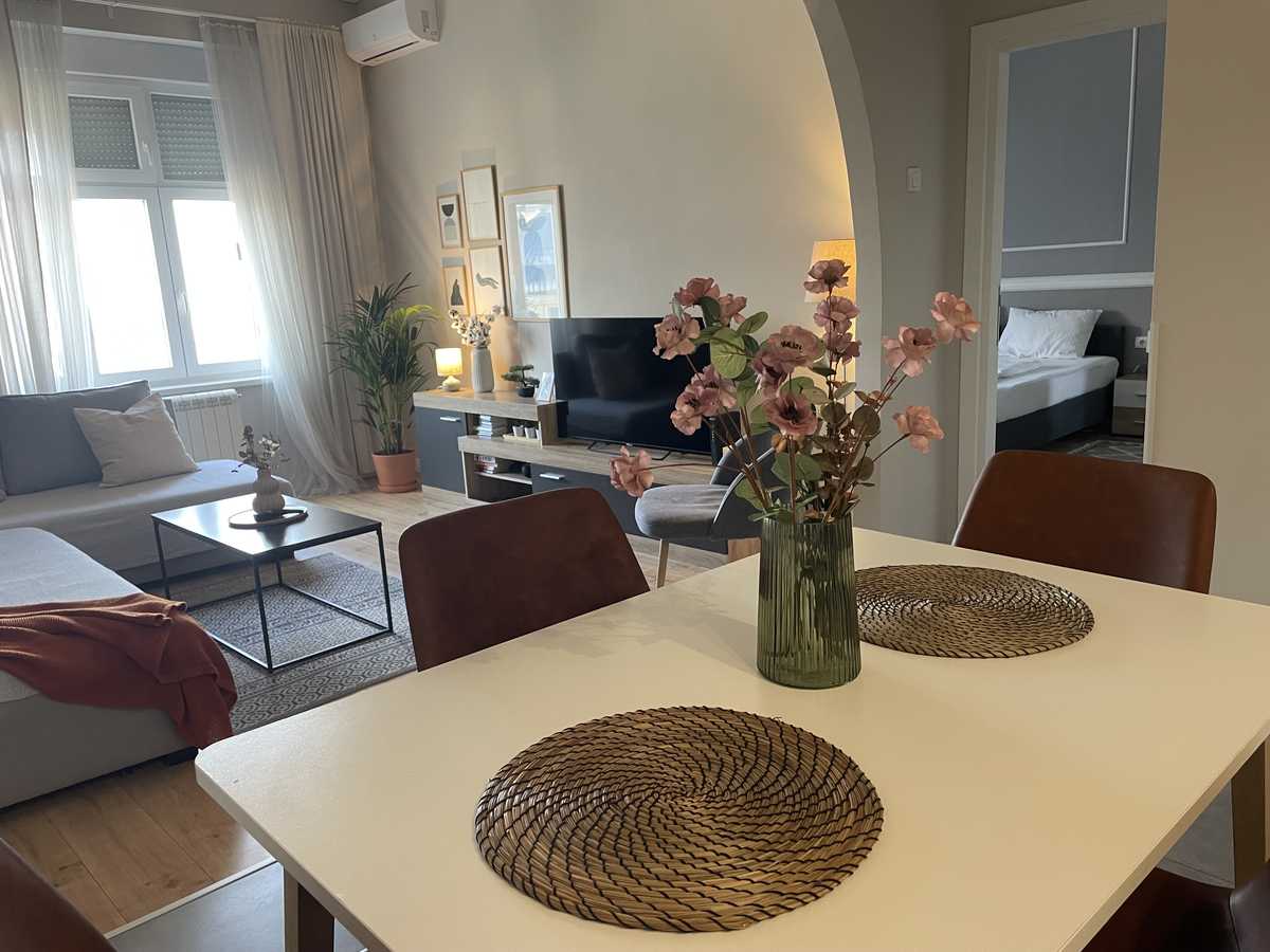 Dining table in the foreground, TV area and view toward the bedroom – Apartment Cityzen – City Break Apartments