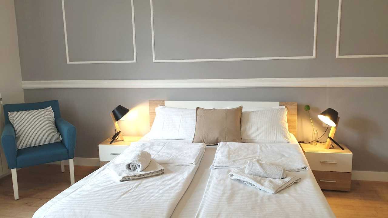 Double bed with two bedside tables and lamps, towels prepared – Apartment Cityzen – City Break Apartments
