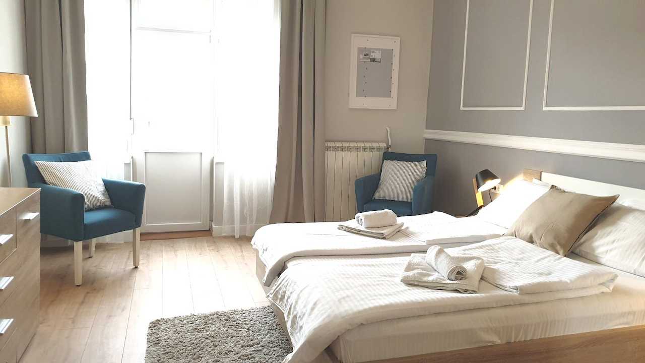 Bedroom with double bed and two blue armchairs near the balcony – Apartment Cityzen – City Break Apartments