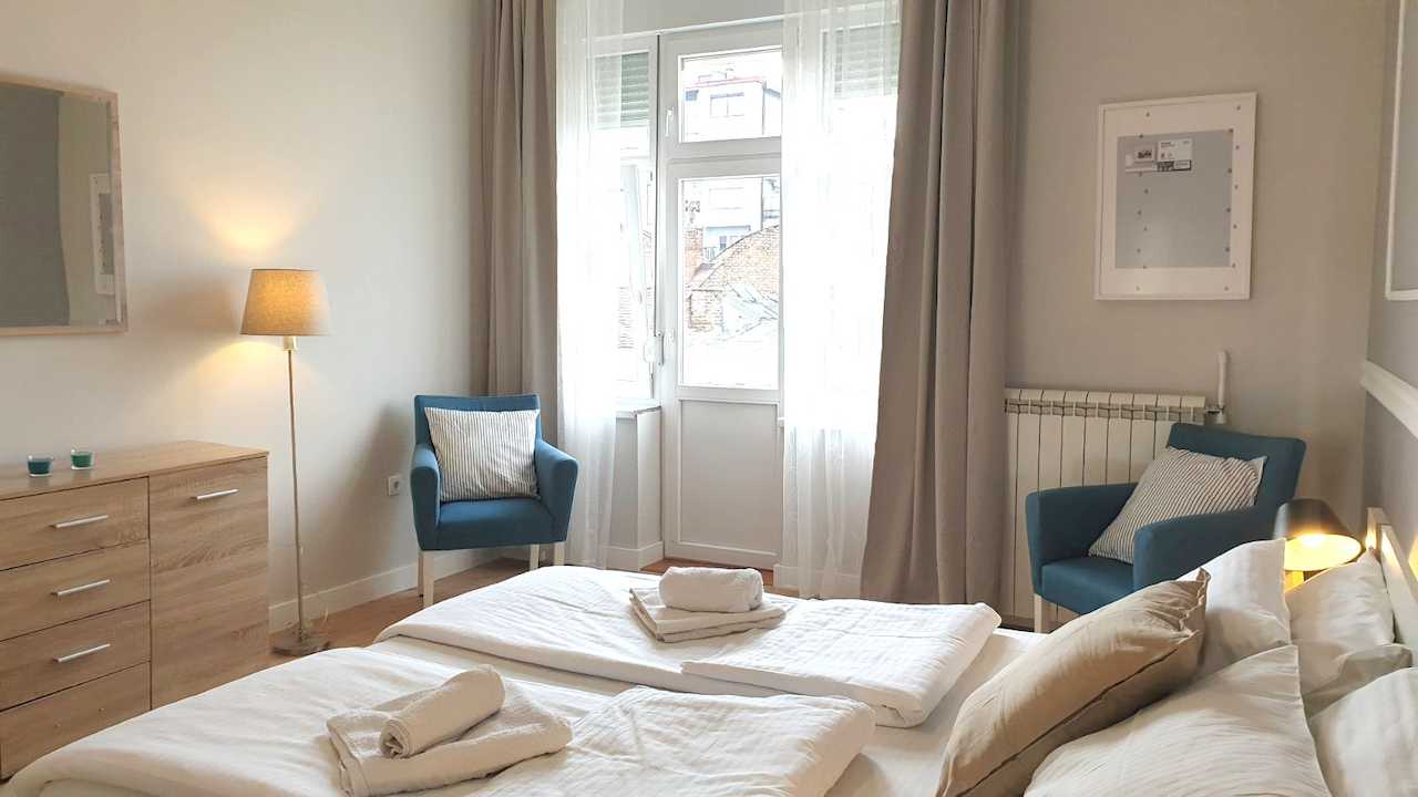 Twin bedroom with two single beds and armchairs by the balcony door – Apartment Cityzen – City Break Apartments