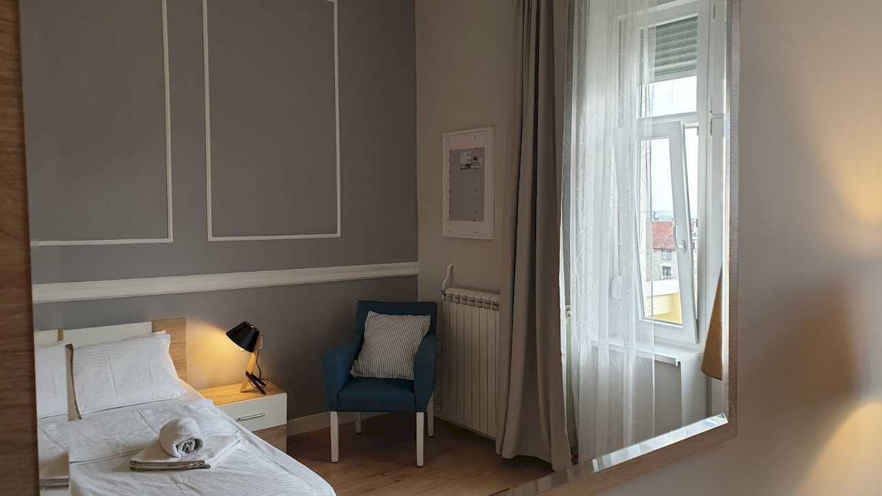 Bedroom with bed, armchair and window with curtains – Apartment Cityzen – City Break Apartments