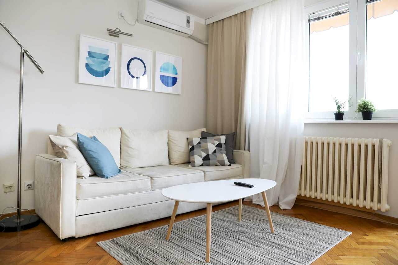 Dnevni boravak sa sofom, klima uređajem i velikim prozorom – Apartman Dolce Vita – City Break Apartments
