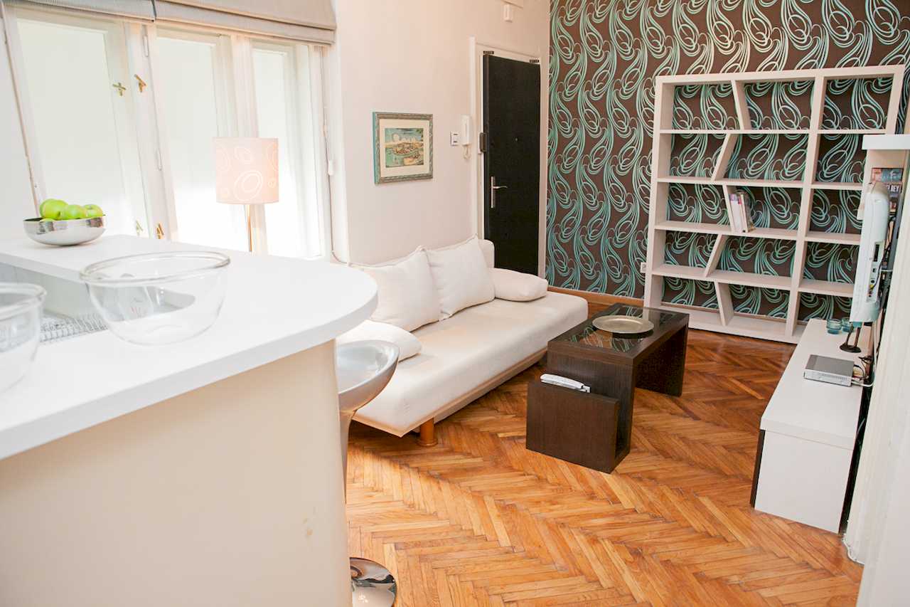 Apartment Downtown (Skadarlija, Belgrade) – living room with white sofa, geometric bookcase and bar