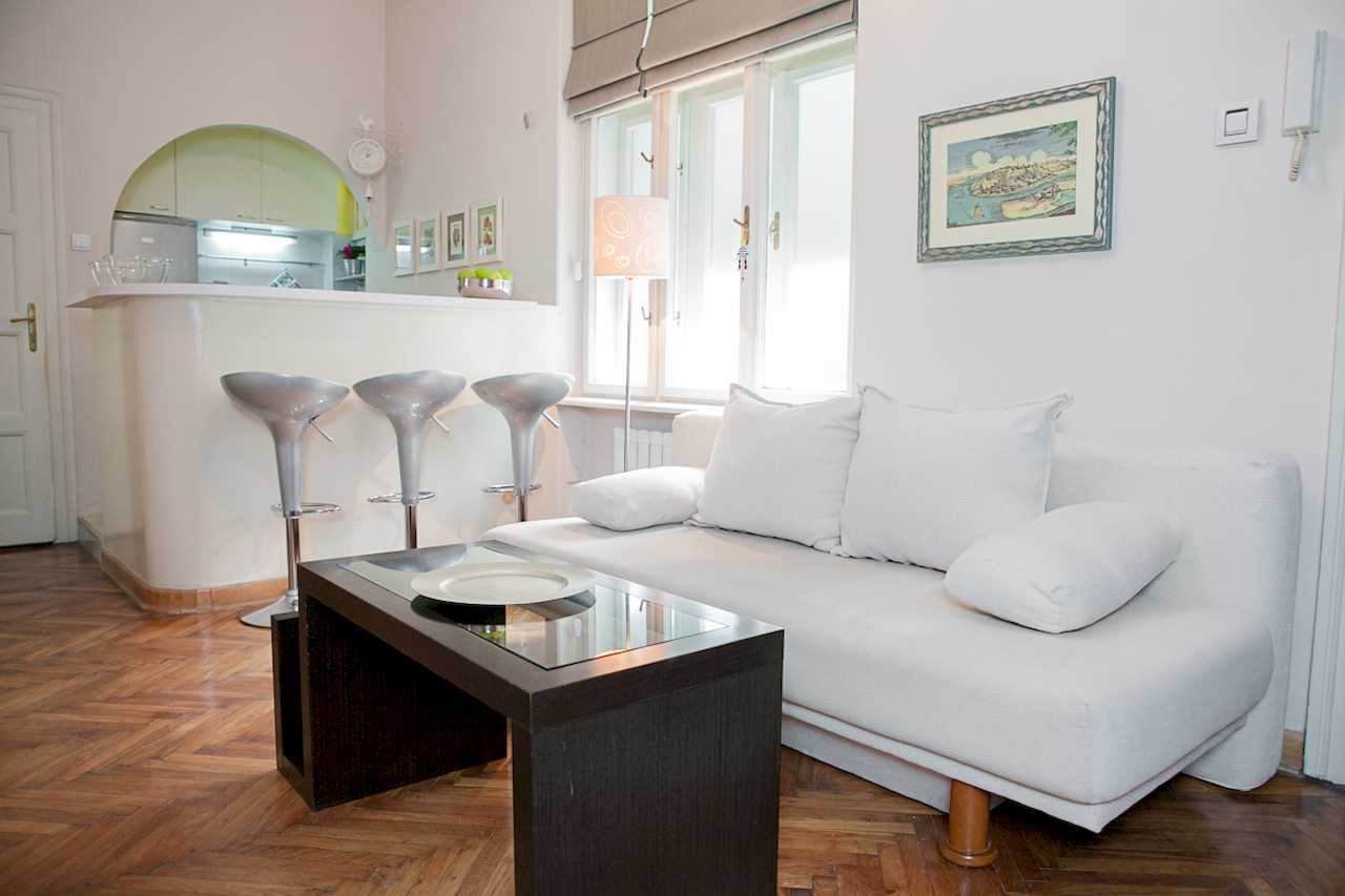 Apartment Downtown (Skadarlija, Belgrade) – living room with white sofa, bar and view to kitchen