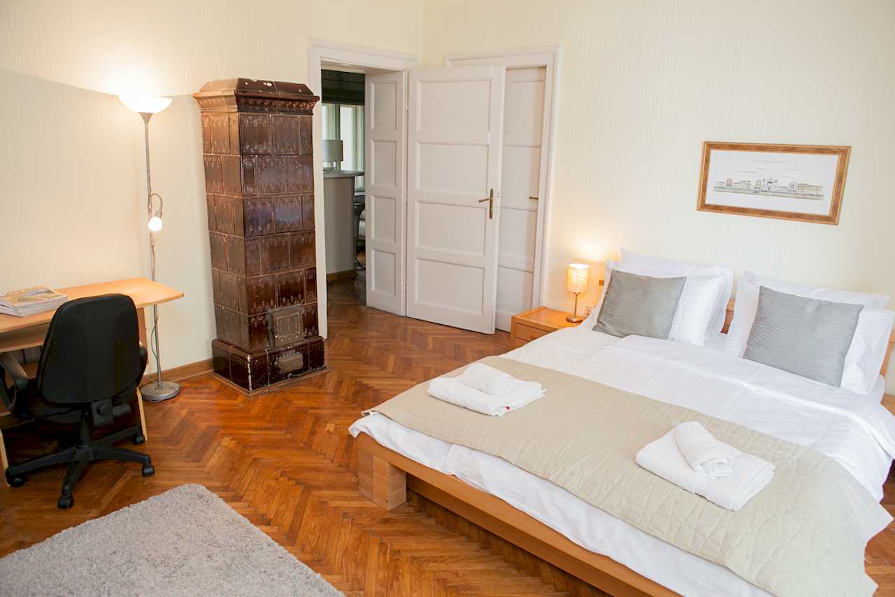 Apartment Downtown (Skadarlija, Belgrade) – bedroom with double bed, desk and tiled stove