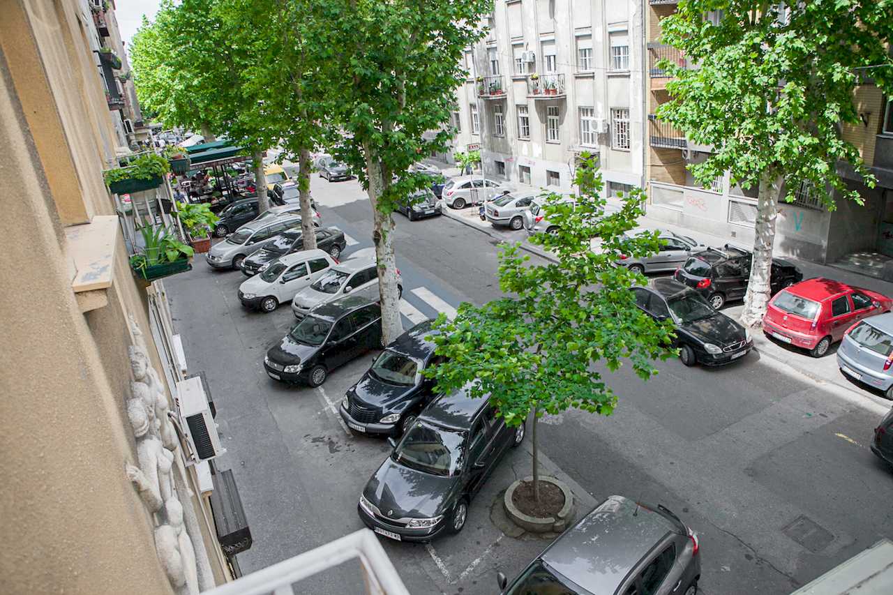 Apartment Downtown (Skadarlija, Belgrade) – view from balcony to tree-lined street and parked cars