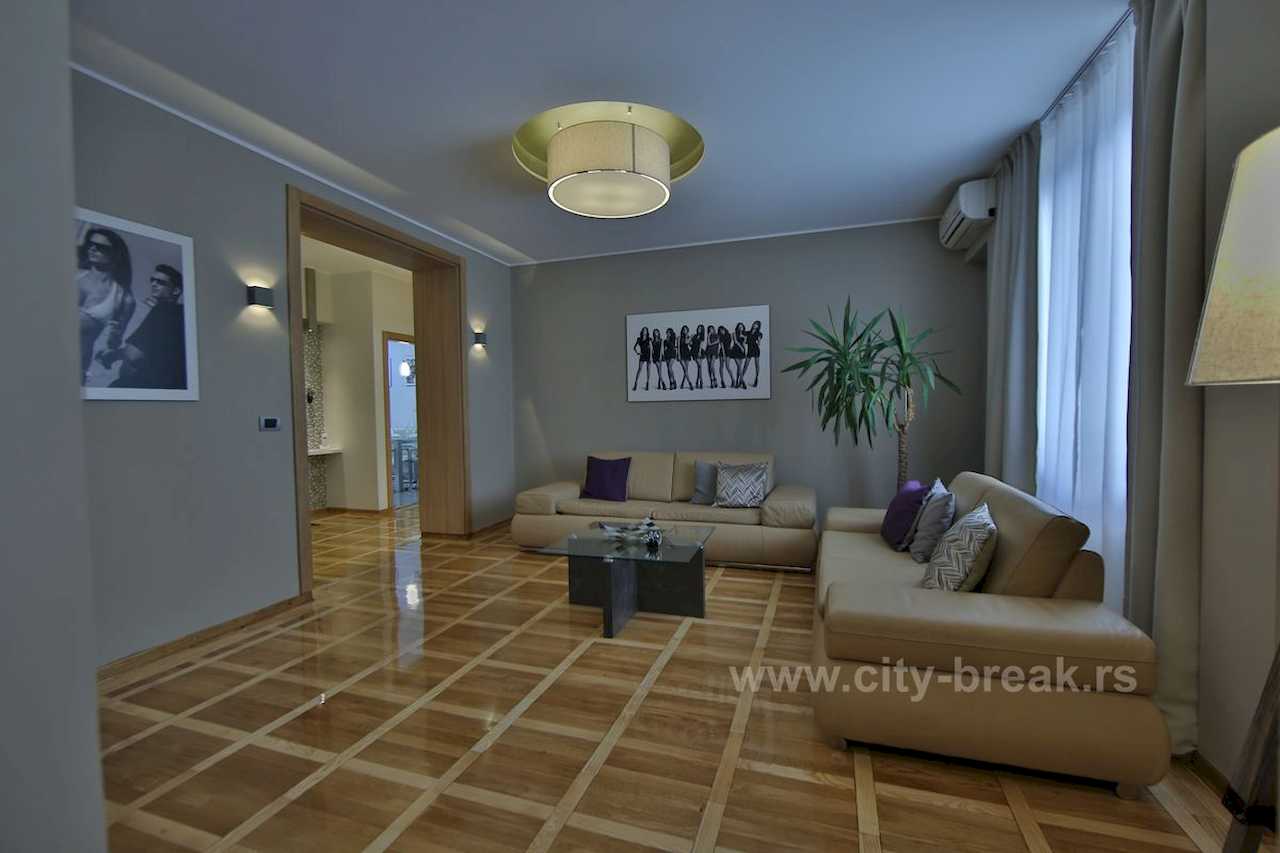 Living room with beige leather sofas, glass coffee table and black-and-white wall art – Apartment Jovanova Lux – City Break Apartments