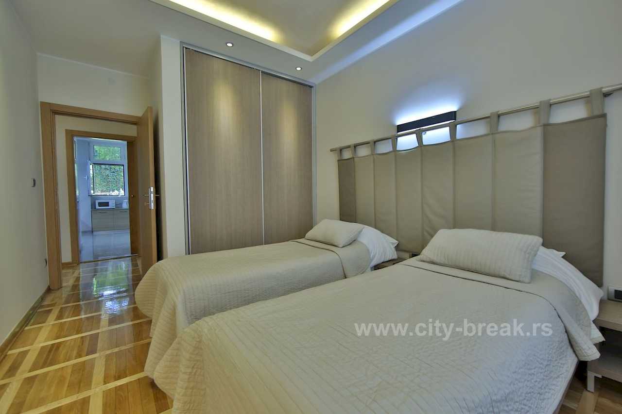 Bedroom with two single beds, built-in wardrobe and sightline toward the kitchen – Apartment Jovanova Lux – City Break Apartments