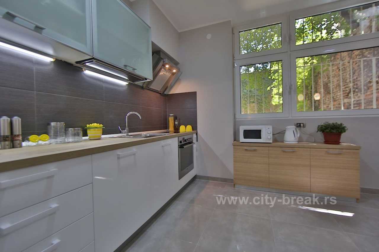Modern kitchen with white cabinets, wood worktop and window – Apartment Jovanova Lux – City Break Apartments
