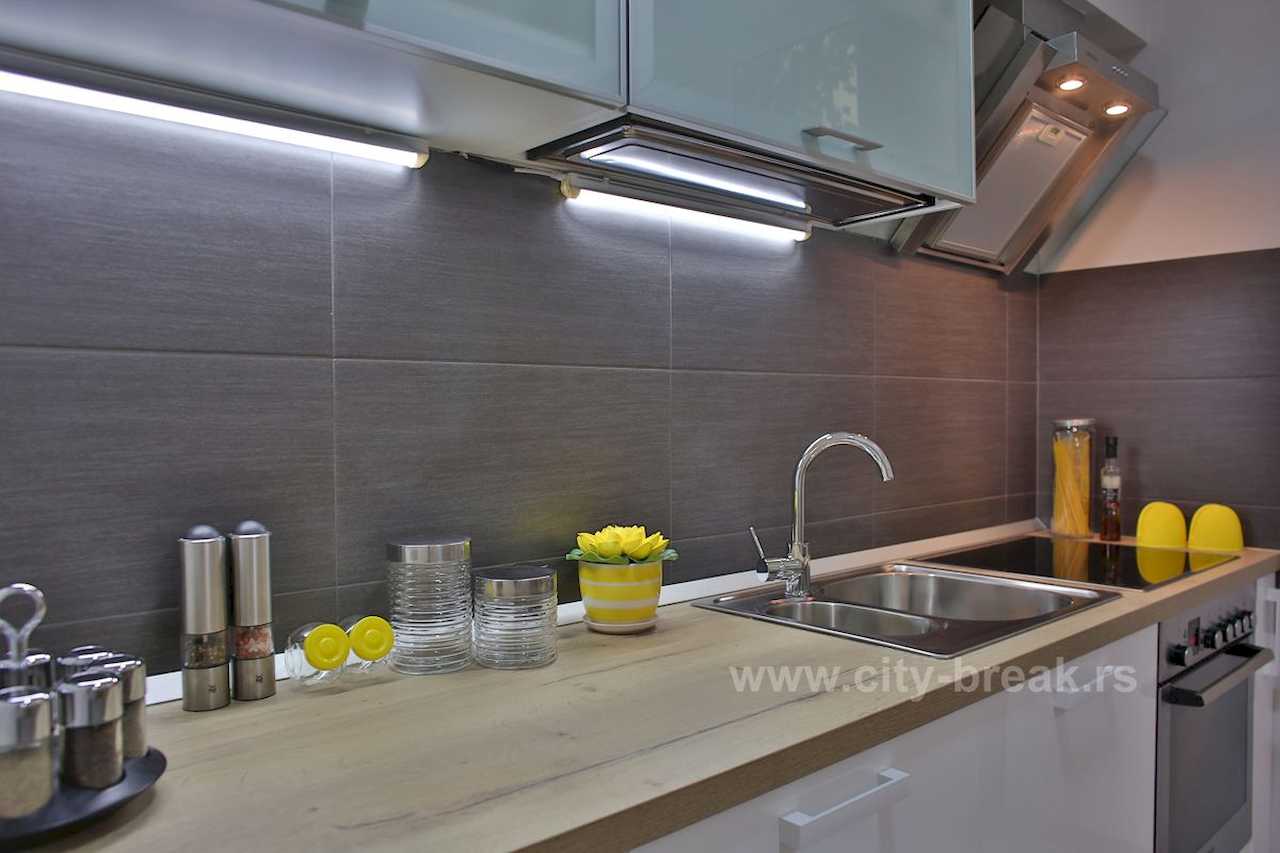 Kitchen detail – wood counter, sink, hob and LED lighting under wall cabinets – Apartment Jovanova Lux – City Break Apartments