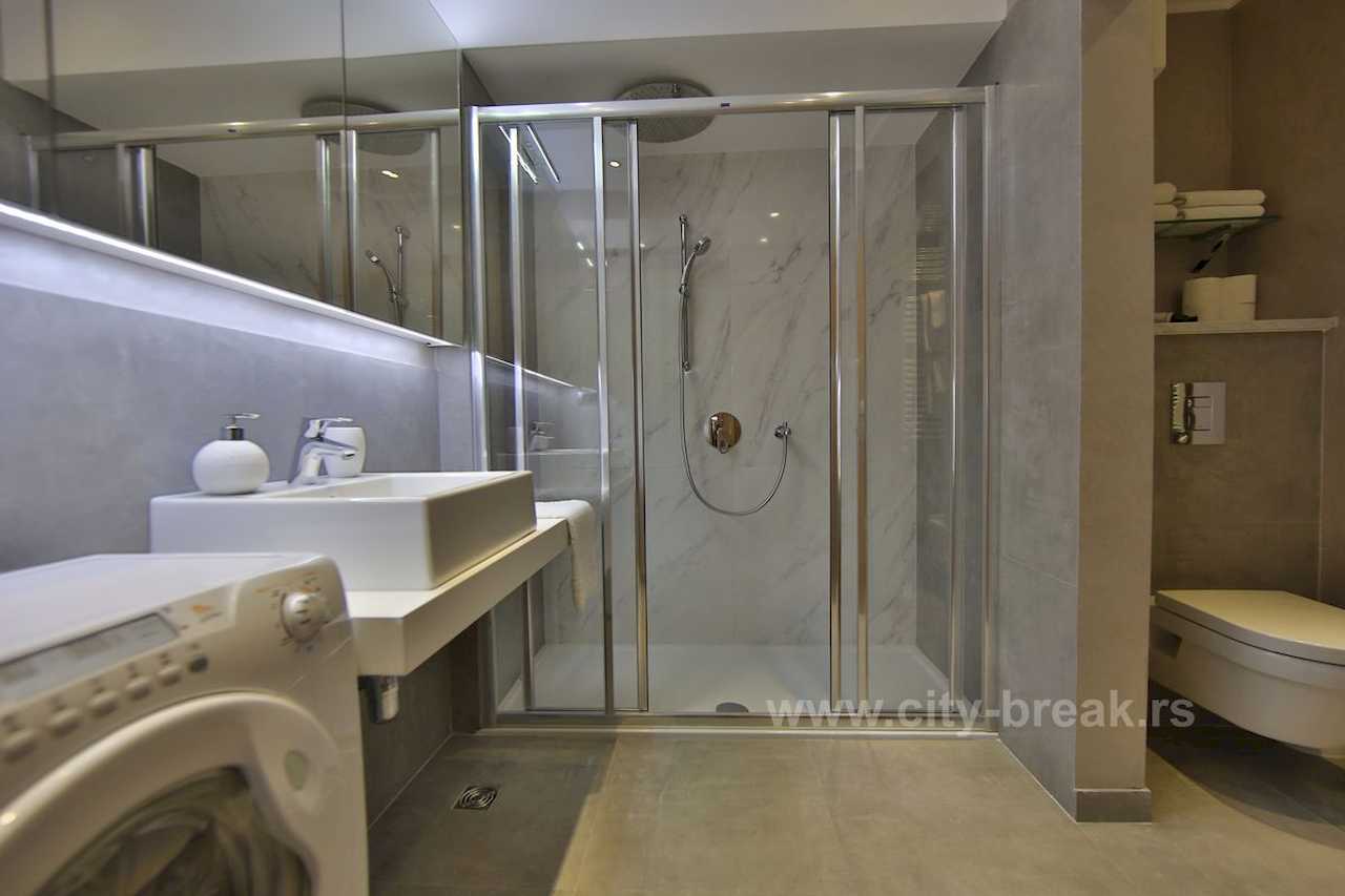 Bathroom with glass shower, vessel sink, wall-hung toilet and washing machine – Apartment Jovanova Lux – City Break Apartments