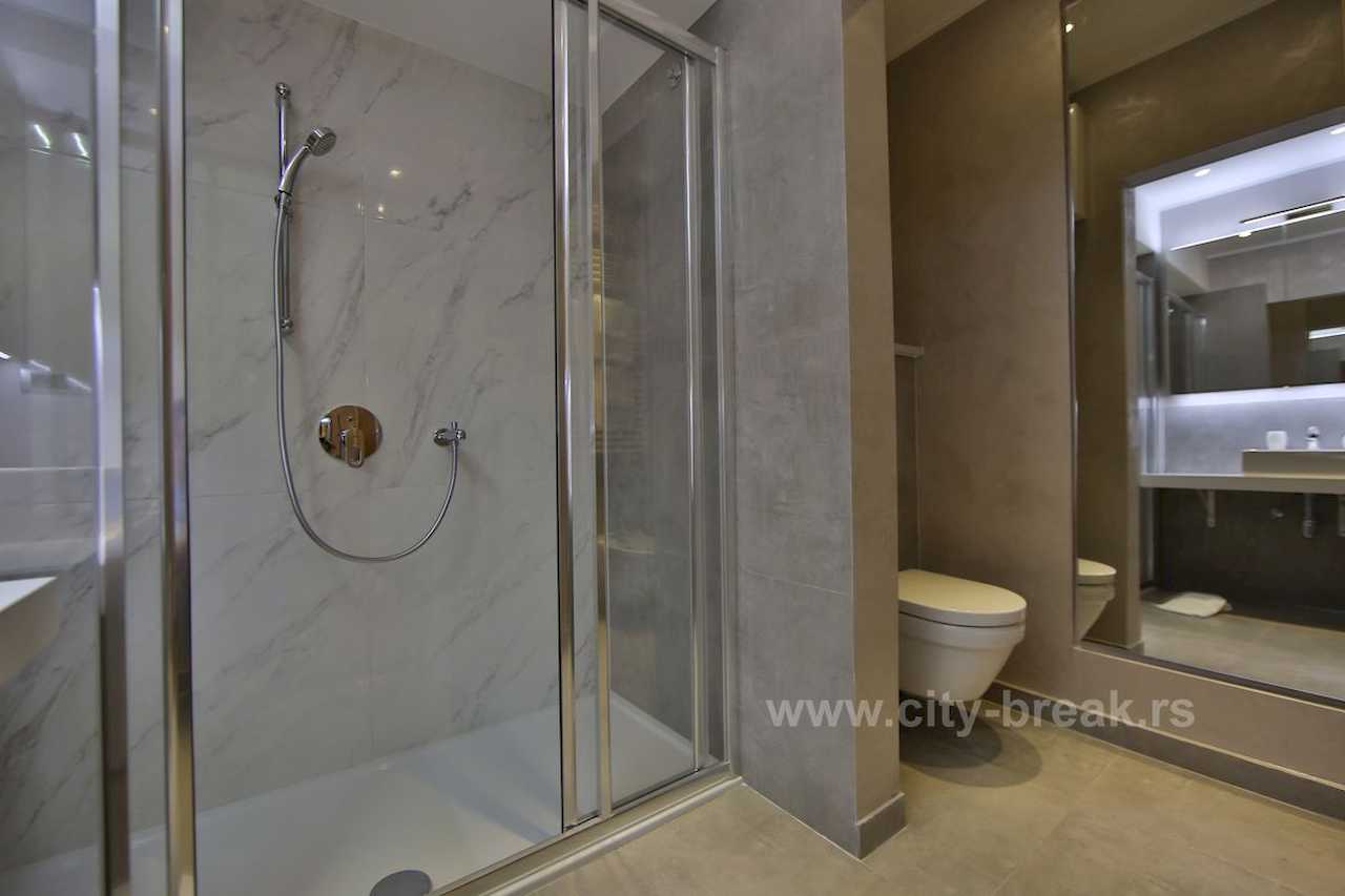 Bathroom with glass shower cabin, wall-hung toilet and full-height mirror – Apartment Jovanova Lux – City Break Apartments