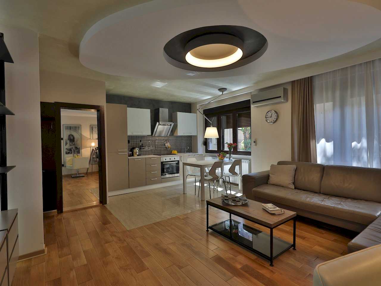 Dnevni boravak sa ugaonom sofom, trpezarijom i kuhinjom u pozadini – Apartman Luna Lux – City Break Apartments