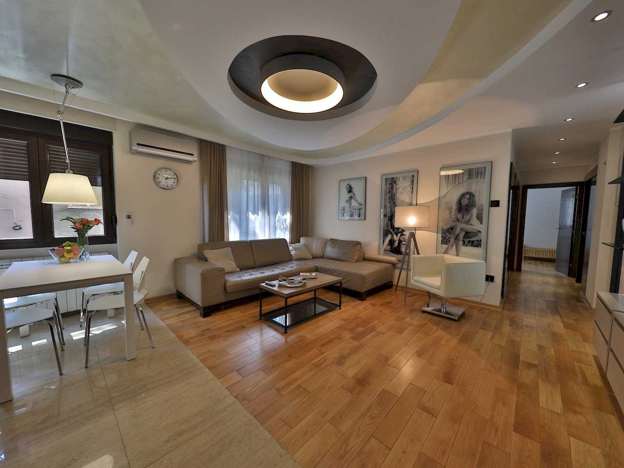 Dnevna soba i trpezarija, ugaona garnitura i tri crno-bele fotografije na zidu – Apartman Luna Lux – City Break Apartments