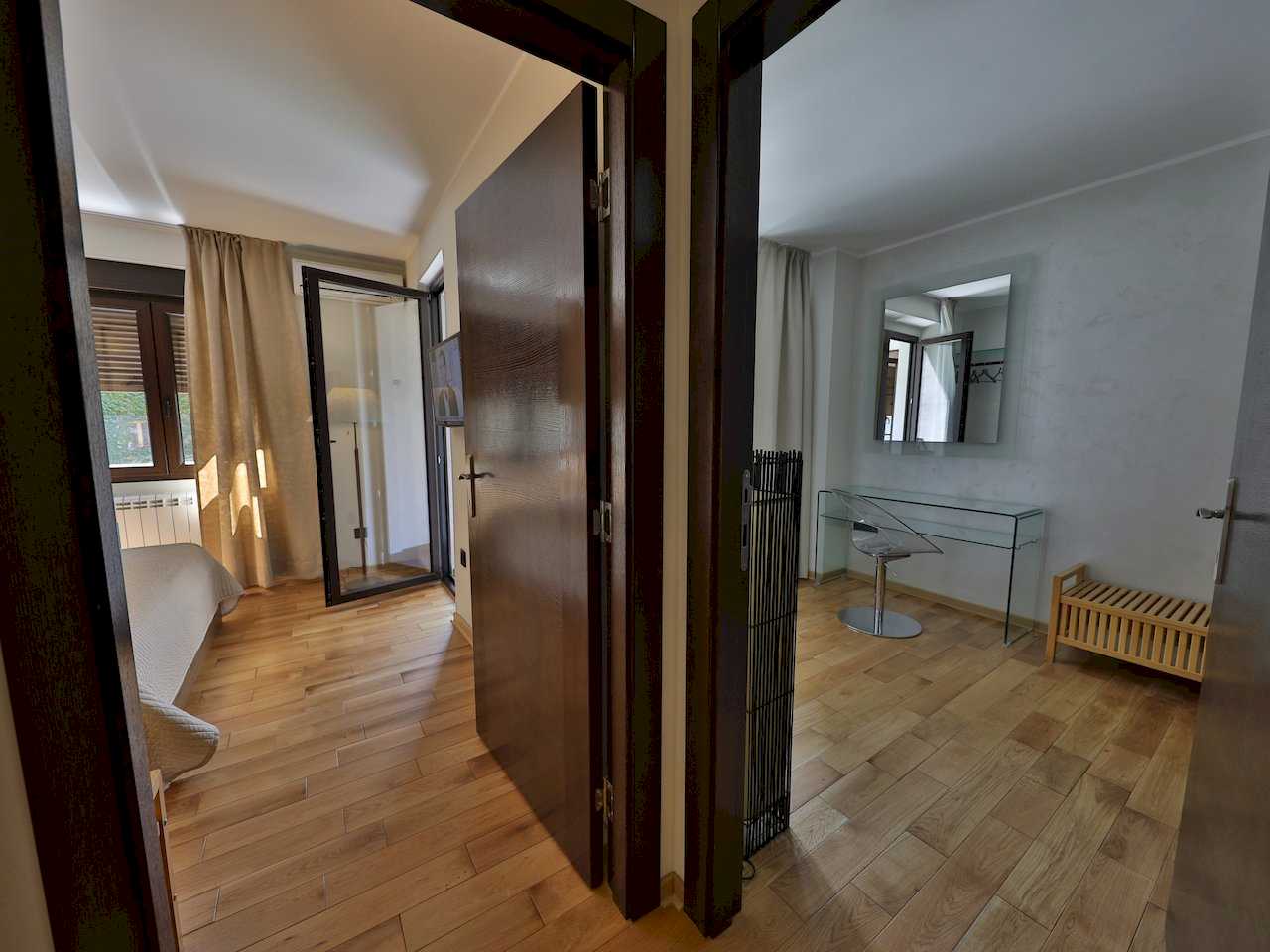 Pogled iz hodnika na spavaću sobu i radni kutak sa staklenim stolom – Apartman Luna Lux – City Break Apartments