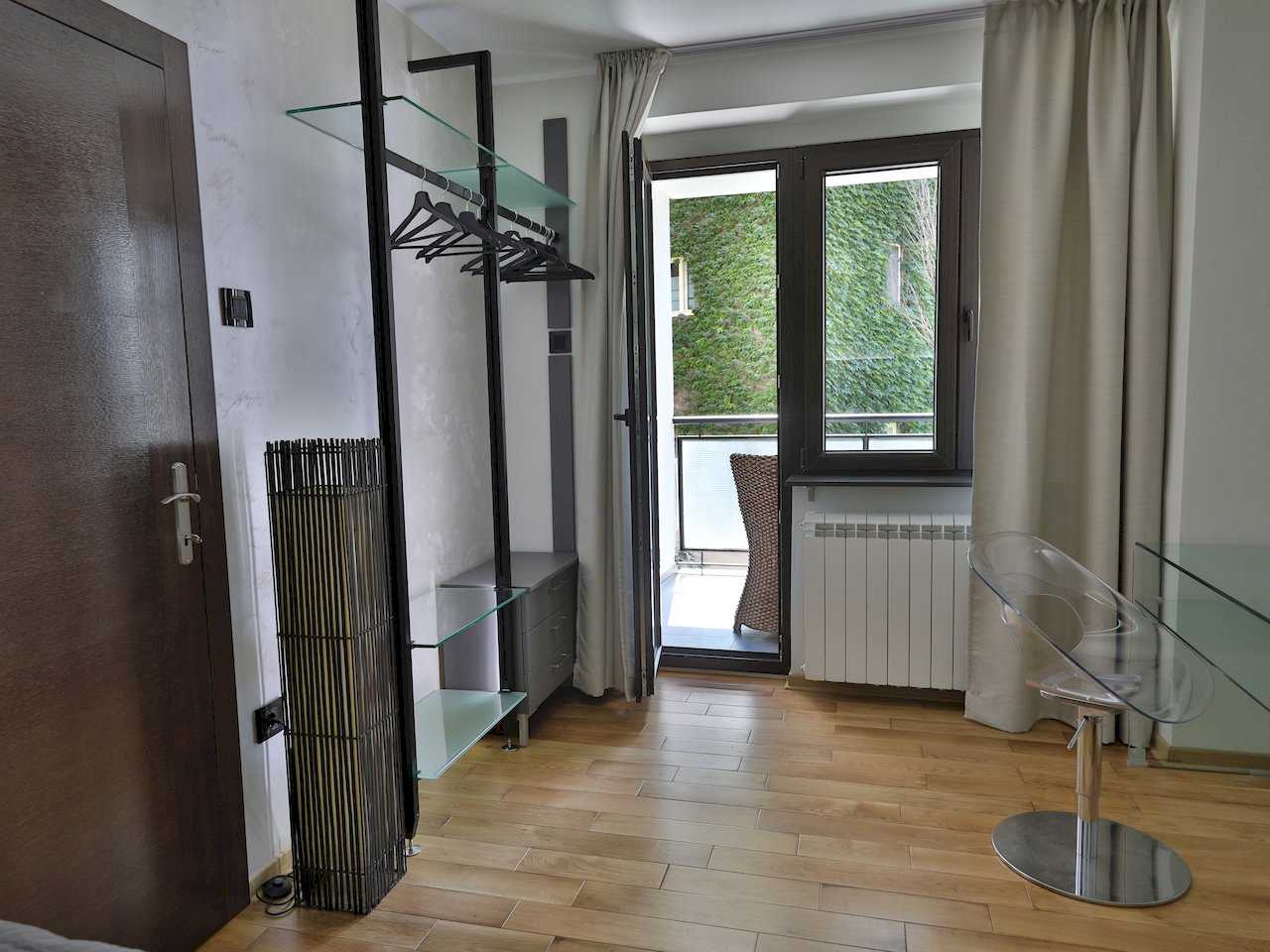 Ugao sobe sa otvorenim garderoberom, providnom stolicom i balkonskim vratima – Apartman Luna Lux – City Break Apartments