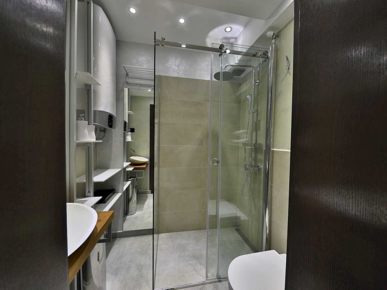 Pogled u kupatilo sa tušem, lavaboom na drvenoj polici i WC-om – Apartman Luna Lux – City Break Apartments