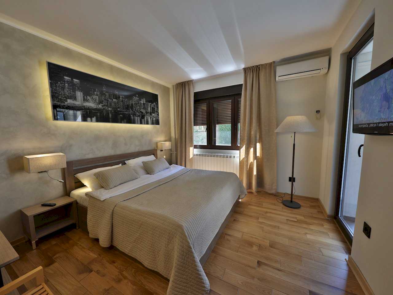 Spavaća soba sa bračnim krevetom, osvetljenom panoramom grada i izlazom na terasu – Apartman Luna Lux – City Break Apartments