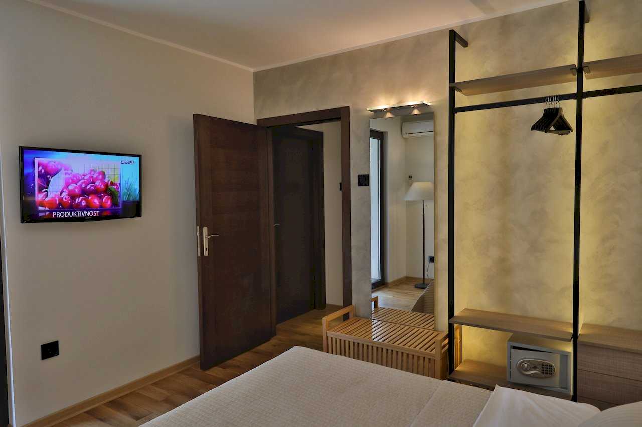 Spavaća soba sa zidnim TV-om, otvorenim garderoberom i sefom – Apartman Luna Lux – City Break Apartments