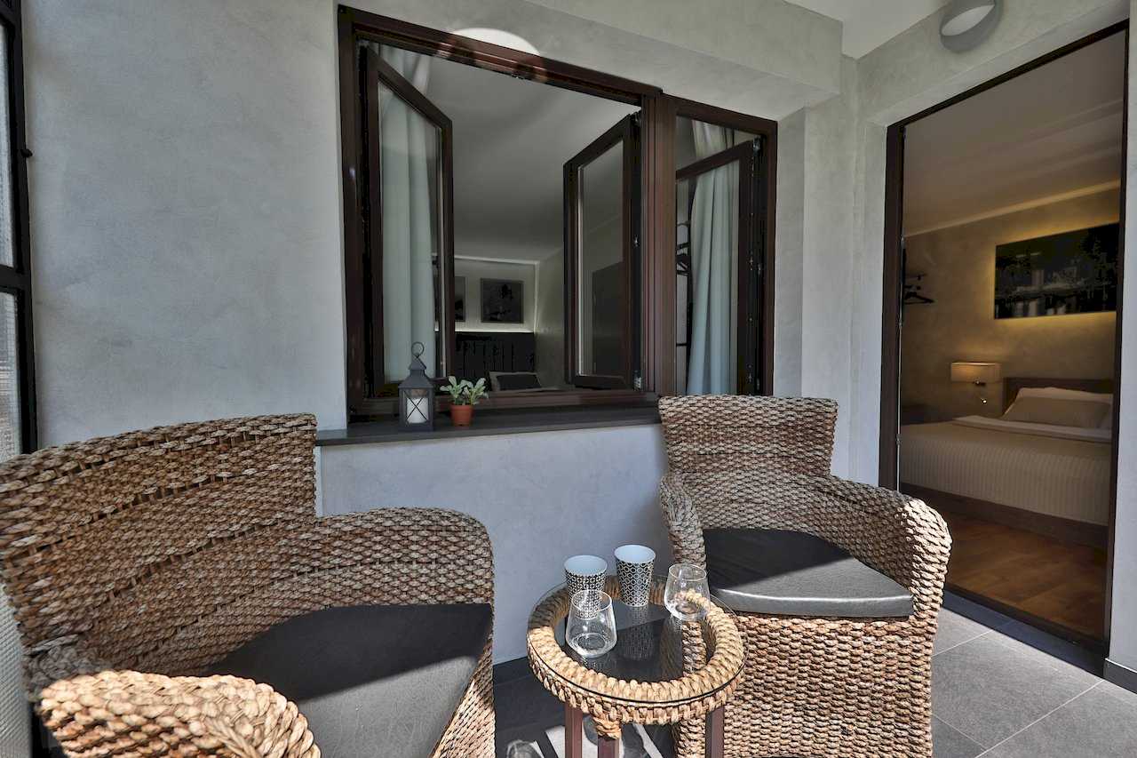 Terasa sa pletenim nameštajem i pogledom kroz prozor u spavaću sobu – Apartman Luna Lux – City Break Apartments