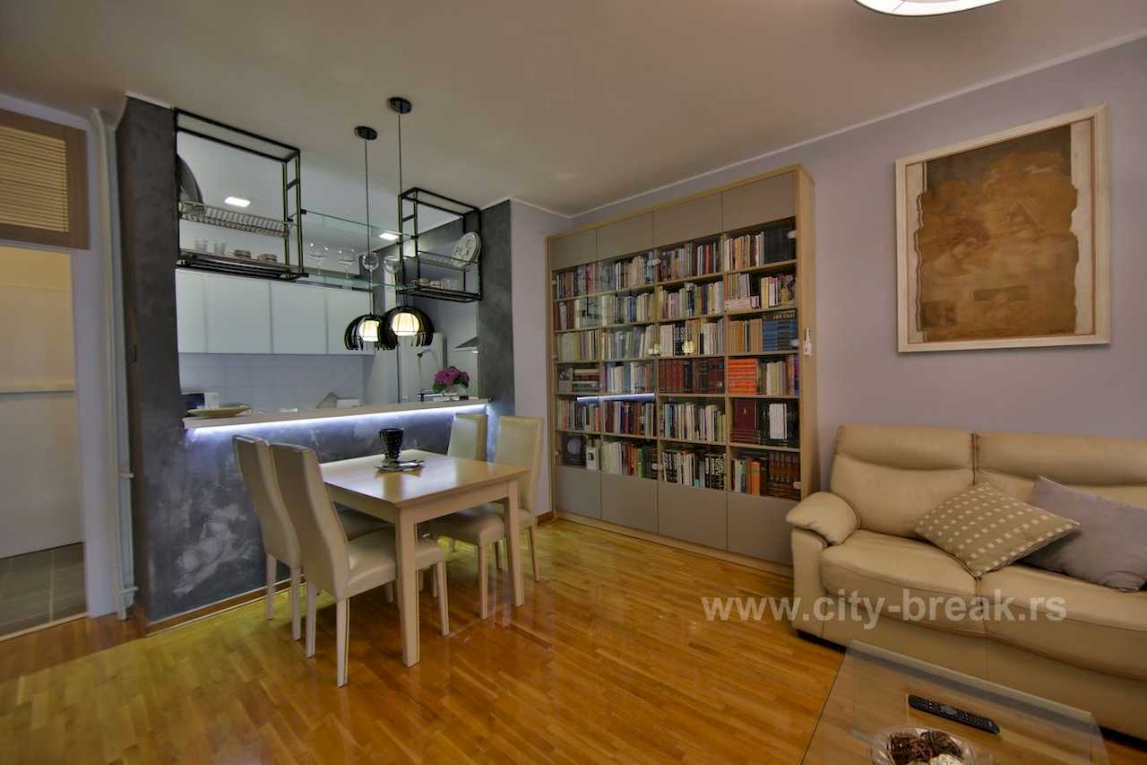 Dnevna soba i trpezarija sa velikom bibliotekom, šankom i crnim visilicama – Apartman Merkator – City Break Apartments
