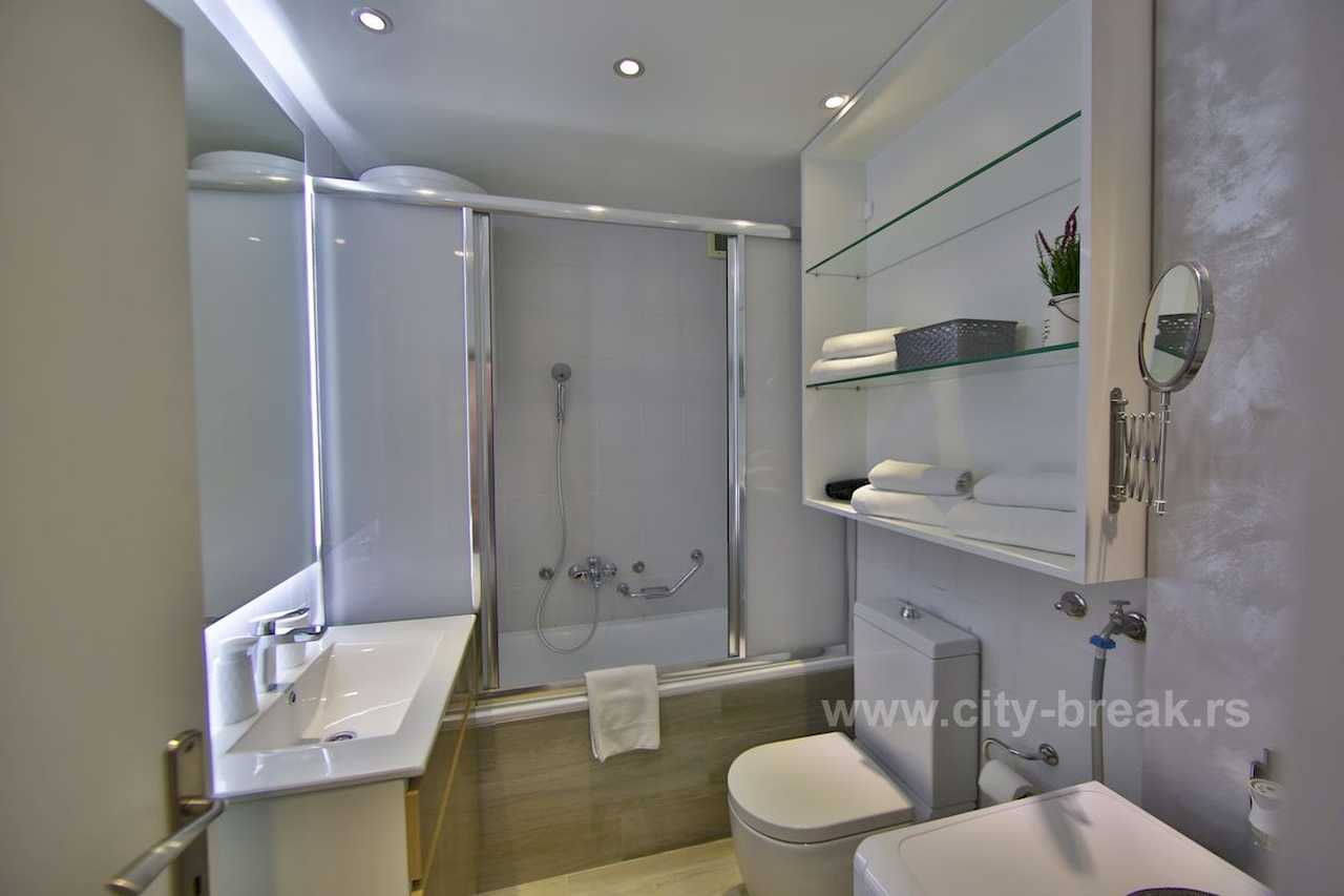 Kupatilo sa kadom, LED ogledalom iznad umivaonika, toaletom i veš mašinom – Apartman Merkator – City Break Apartments