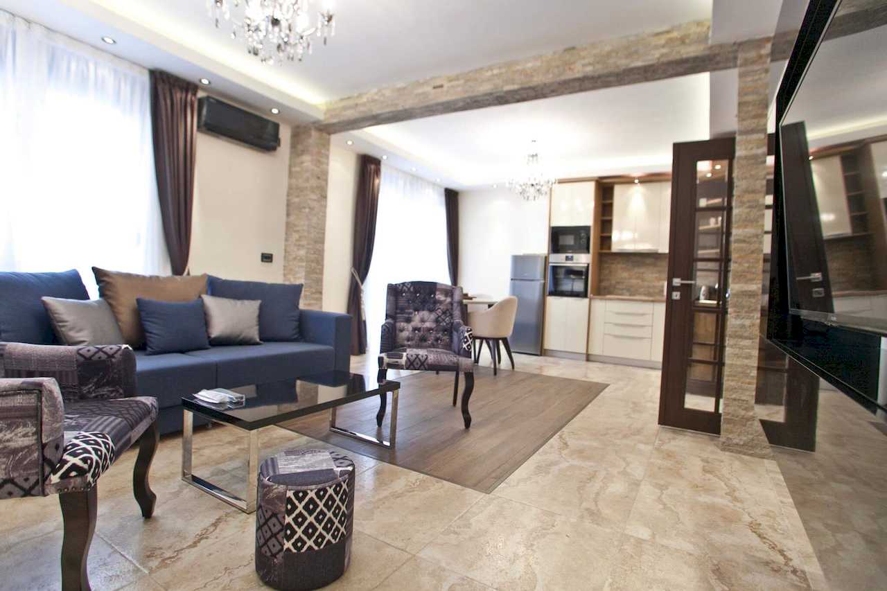 Otvoren prostor – dnevna soba, kuhinja i trpezarija sa kamenim stubovima i kristalnim lusterima – Apartman Molerova – City Break Apartments