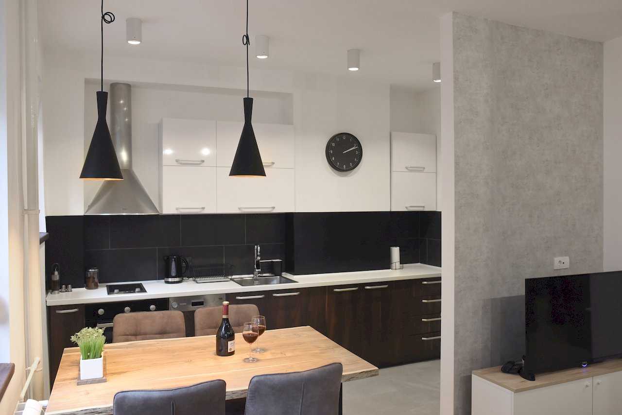 Moderna kuhinja sa belo-tamnim elementima i trpezarijski sto sa vinom – Apartman Mondo 2 – City Break Apartments
