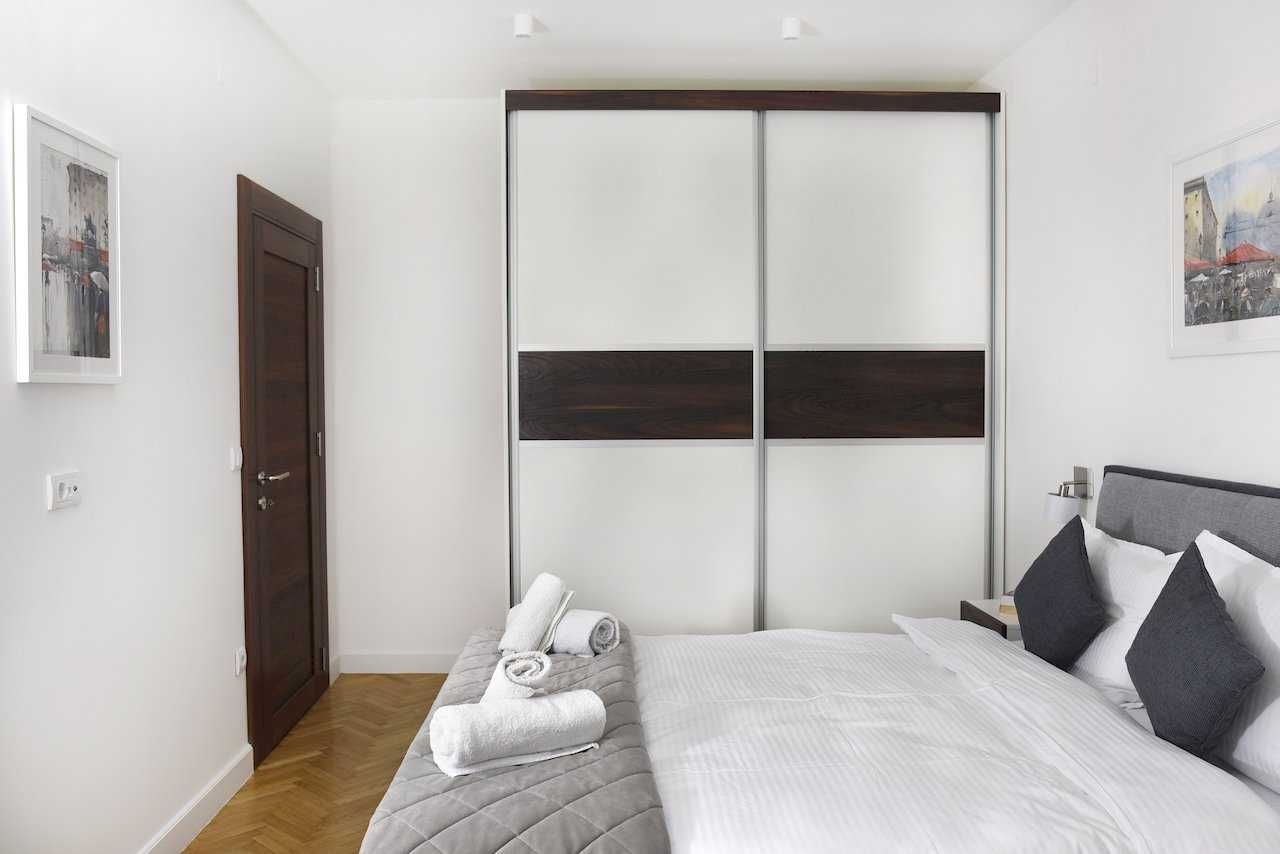 Spavaća soba sa bračnim krevetom, ugradnim plakarom i uokvirenim slikama – Apartman Mondo 2 – City Break Apartments