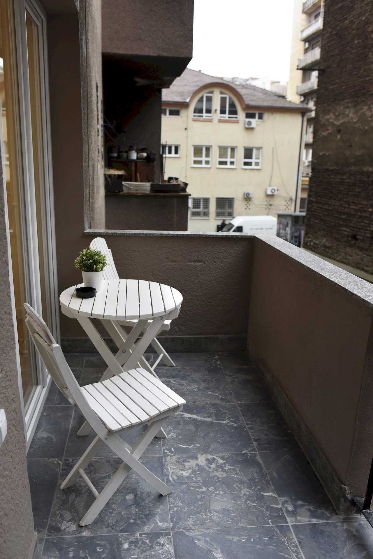 Terasa sa belim stolom i stolicama i pogledom na gradske zgrade – Apartman Mondo 2 – City Break Apartments