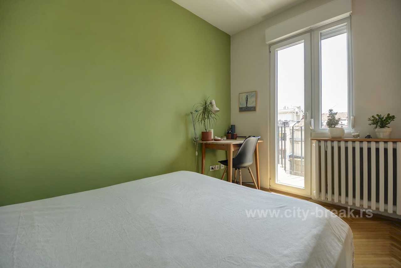 Apartman NINA (Vračar, Beograd) – spavaća soba sa radnim stolom, zelenim akcentnim zidom i izlazom na terasu