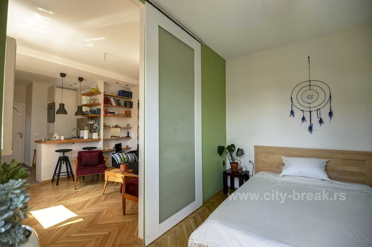 Apartman NINA (Vračar, Beograd) – pogled iz spavaće na dnevni boravak i kuhinju kroz bela klizna vrata