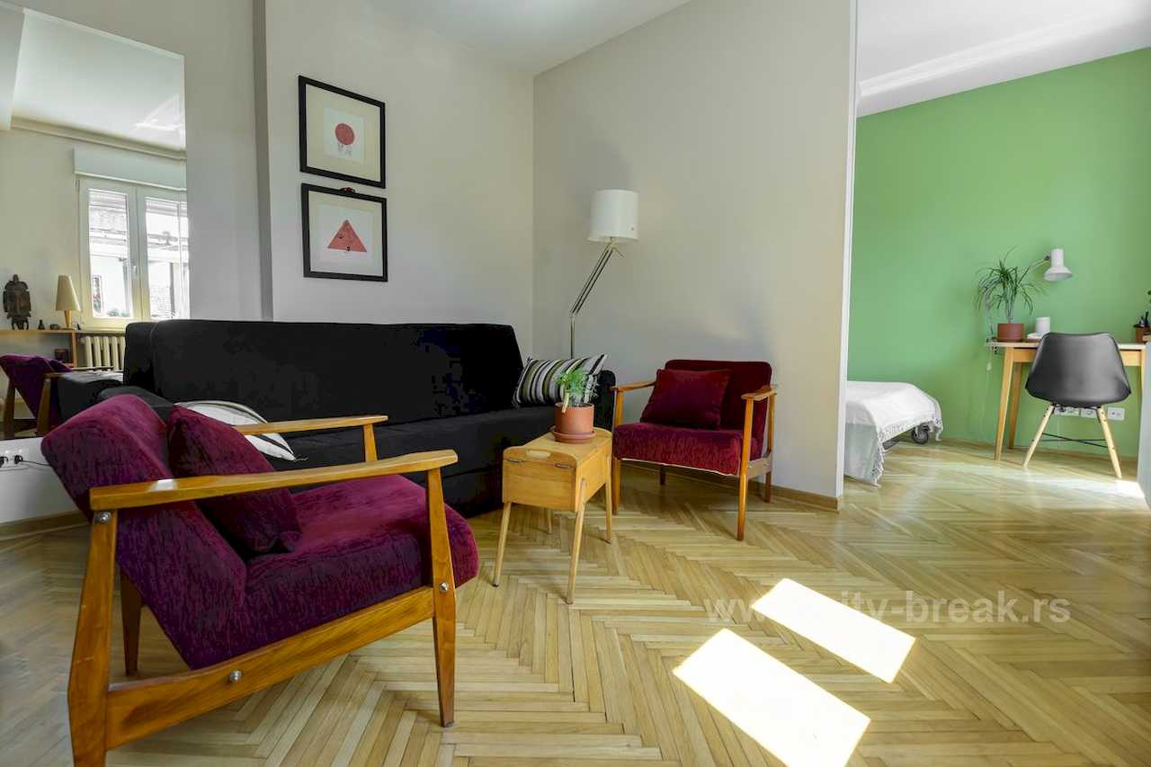 Apartman NINA (Vračar, Beograd) – dnevna sa ljubičastim foteljama i pogledom na radni kutak sa zelenim zidom