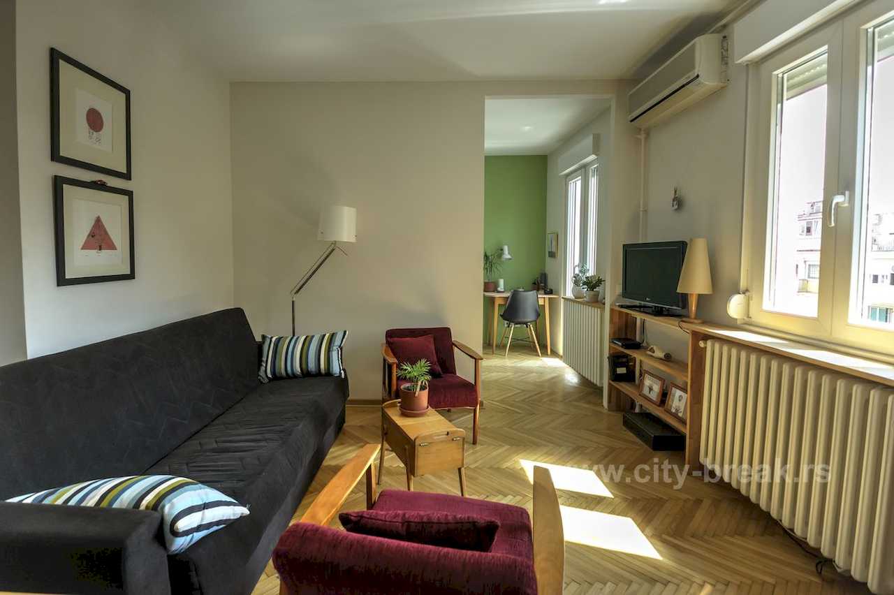 Apartman NINA (Vračar, Beograd) – dnevna sa crnom sofom, bordo foteljama i pogledom na radni kutak