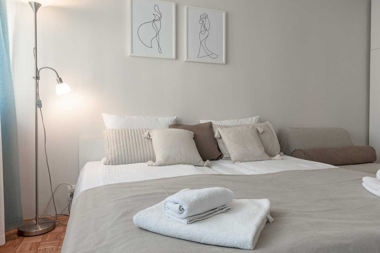Double bed with pillows, line-art prints above the headboard, and floor lamp – Apartment Oaza – City Break Apartments