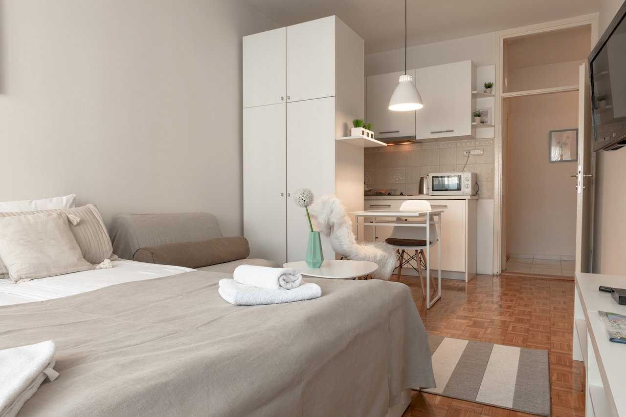 Studio overview: bed, white wardrobe, kitchenette, and dining table – Apartment Oaza – City Break Apartments