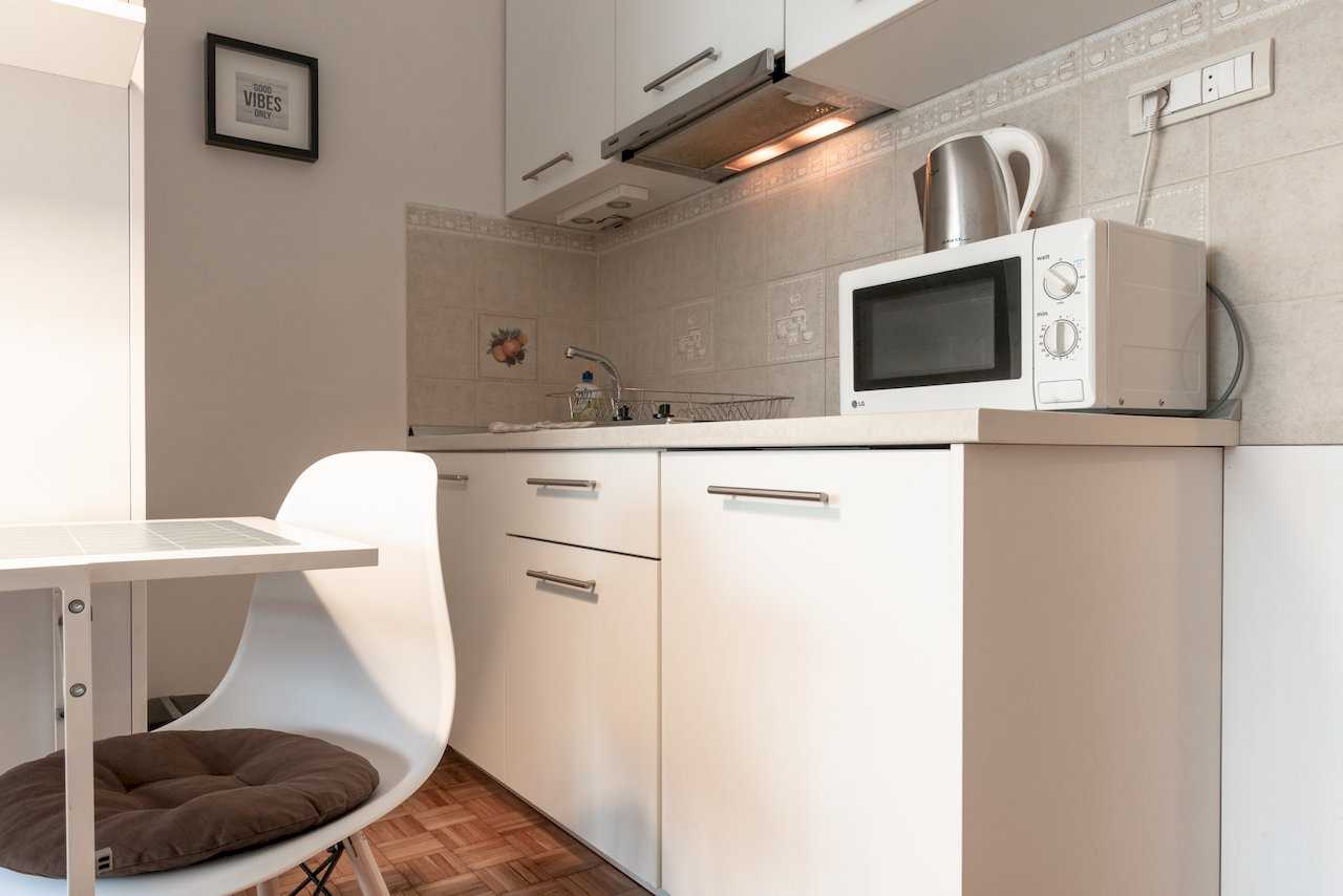 White kitchen with microwave, sink, and white dining chair – Apartment Oaza – City Break Apartments