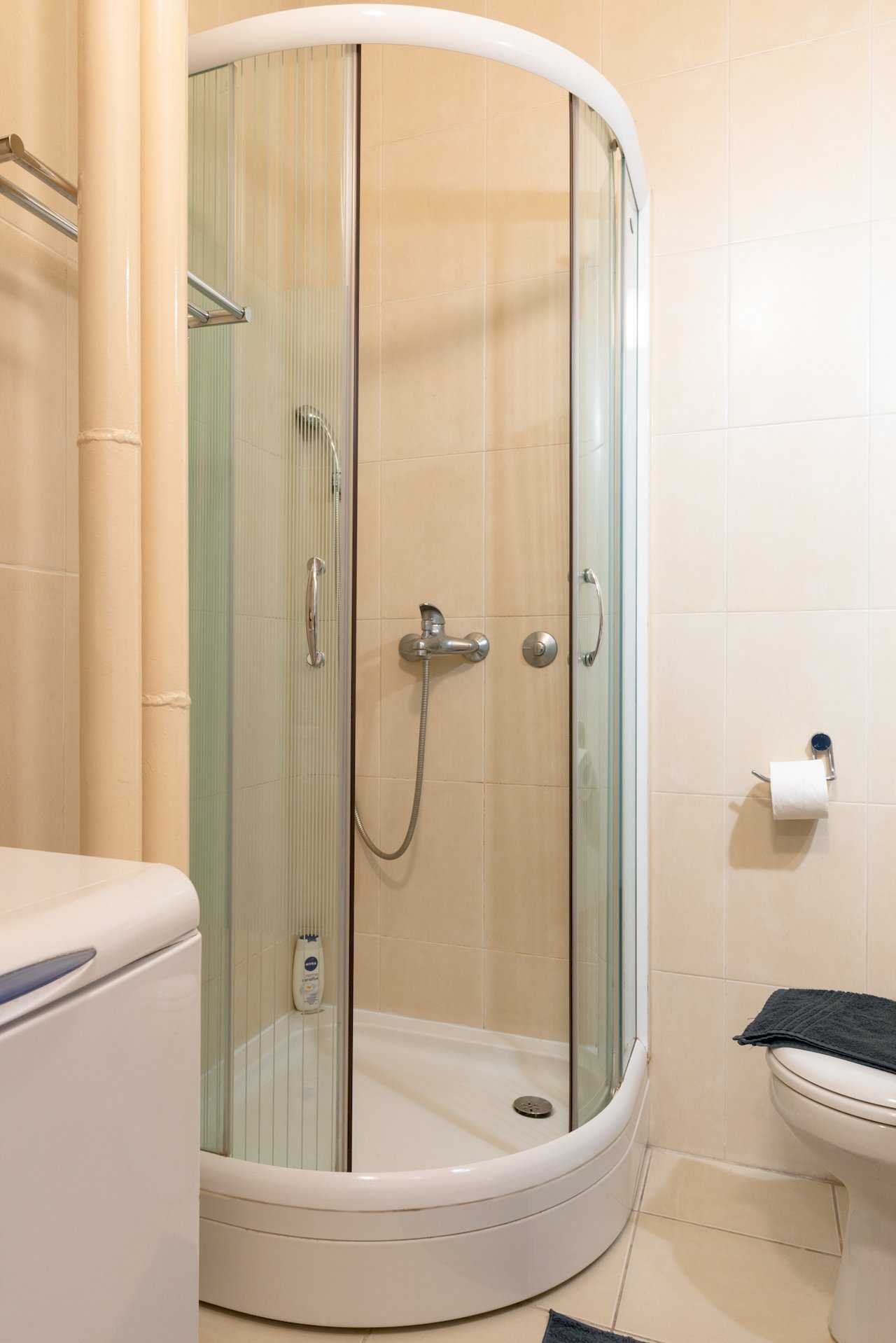 Bathroom with curved shower enclosure, toilet, and washing machine – Apartment Oaza – City Break Apartments