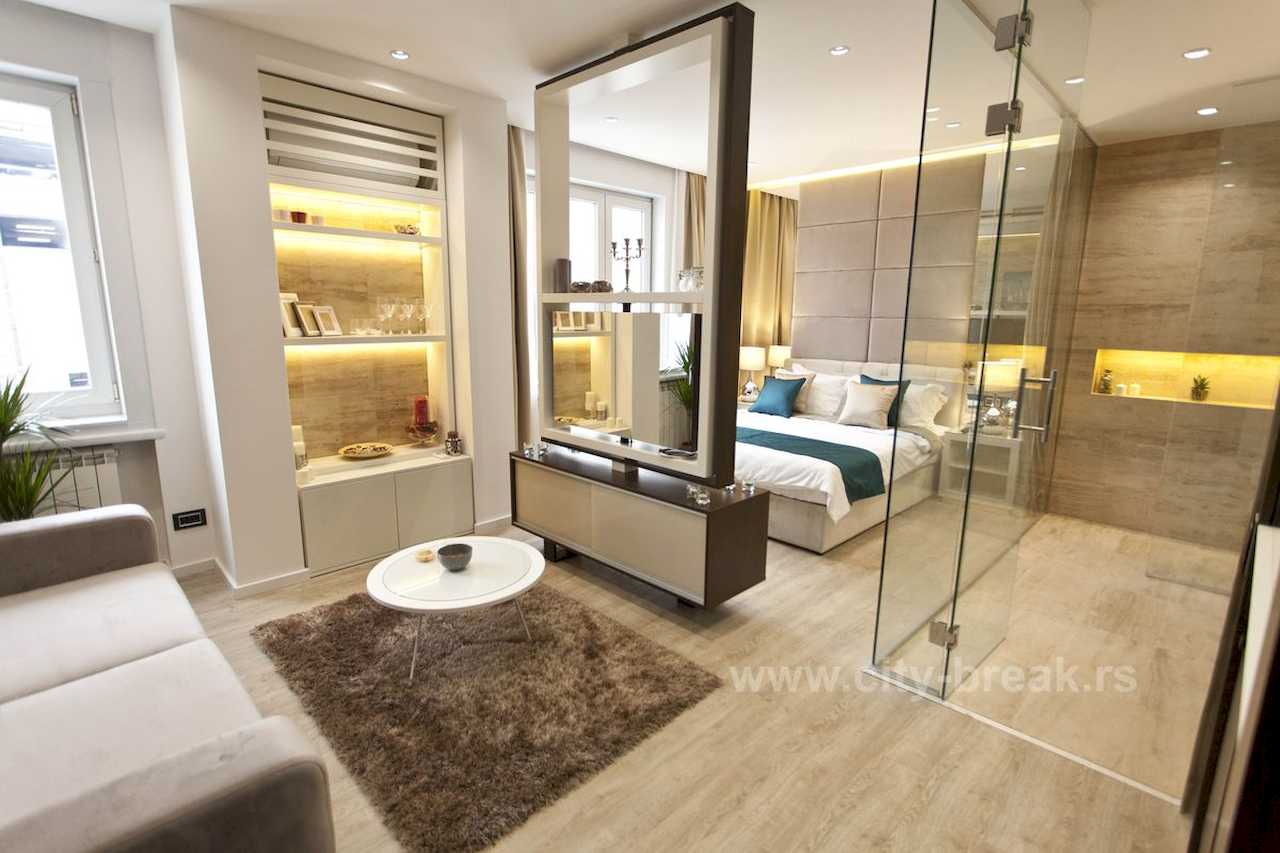 Apartman Obilić (Obilićev venac, Beograd) – dnevni boravak sa dvosedom i osvetljenom vitrinom, pogled ka spavaćem delu i staklenom kupatilu