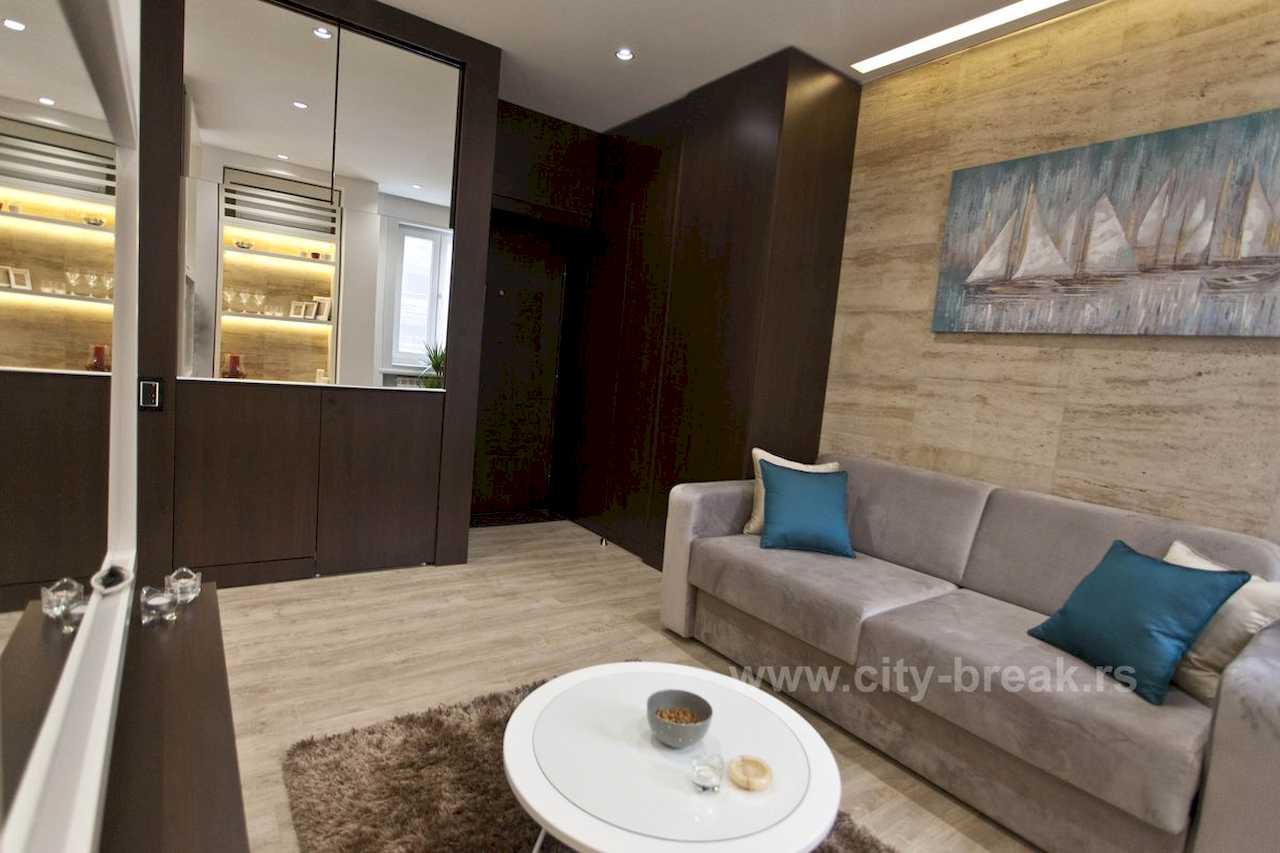 Apartman Obilić (Obilićev venac, Beograd) – dnevni boravak sa trosedom, klub-stolom, slikom jedrenjaka i osvetljenom vitrinom