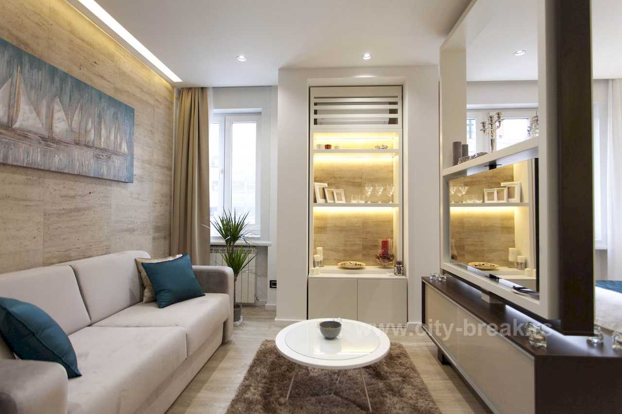 Apartman Obilić (Obilićev venac, Beograd) – dnevni boravak sa trosedom i osvetljenim vitrinama uz travertinski zid